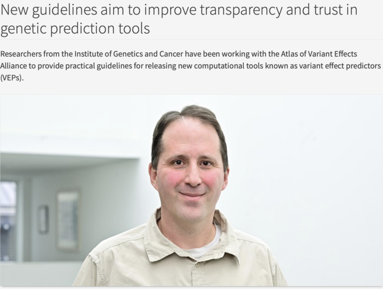 The image features a person with short dark hair, wearing a beige collared shirt. They are smiling softly while standing against a plain, light-colored background. In the top section of the image, there is text describing new guidelines for genetic prediction tools. The background includes blurred elements such as wall decor and light from a window, adding a subtle depth to the composition.